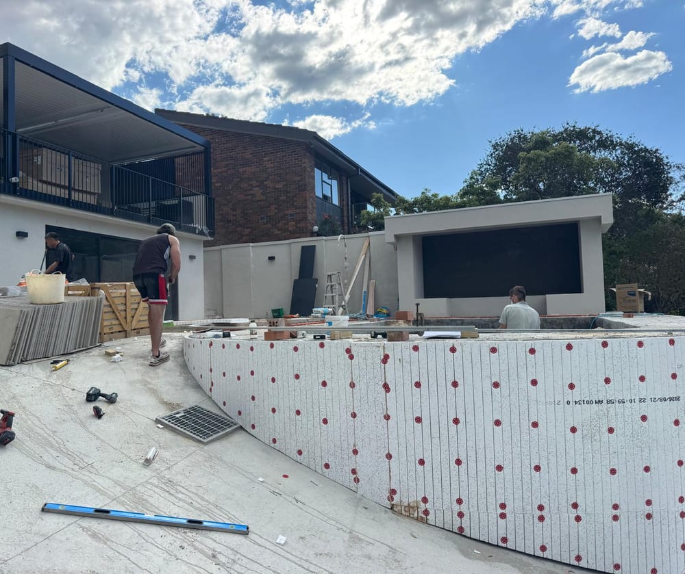 Nabilton Group crew working around a curved raised pool wall at a residential build