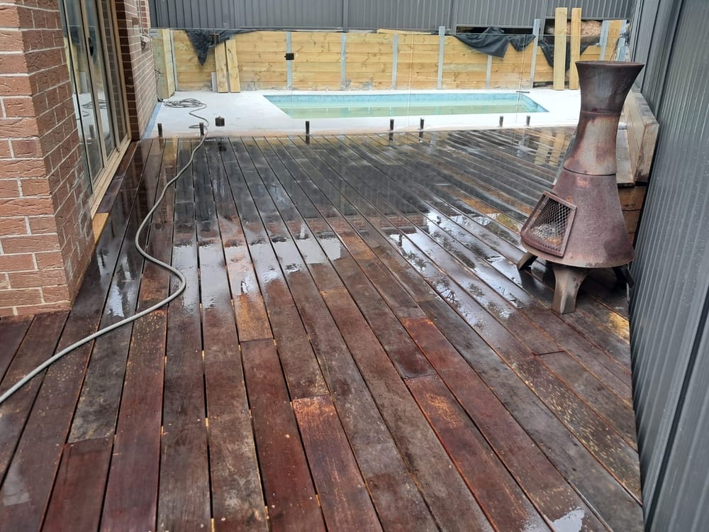 Hardwood deck leading to a finished pool behind frameless glass fencing