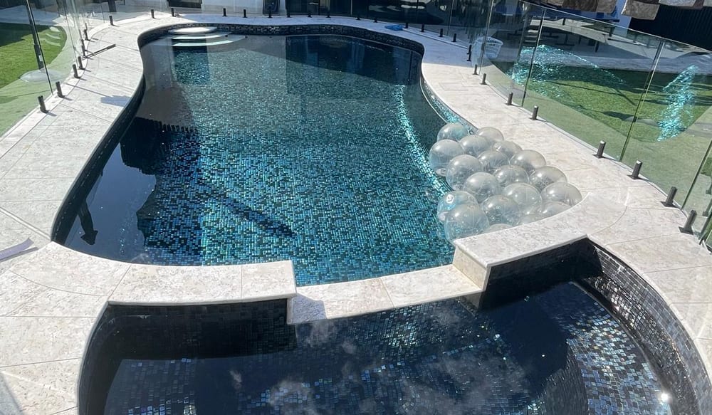 Finished Nabilton Group pool tiled in blue-green mosaic, with a round mosaic spa alongside