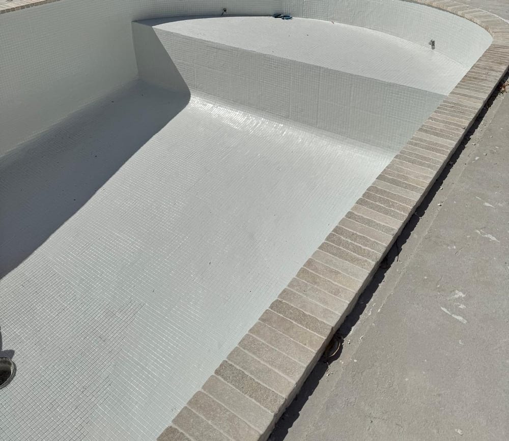 Tiled bench seat and step inside a pool shell, coping laid around the edge
