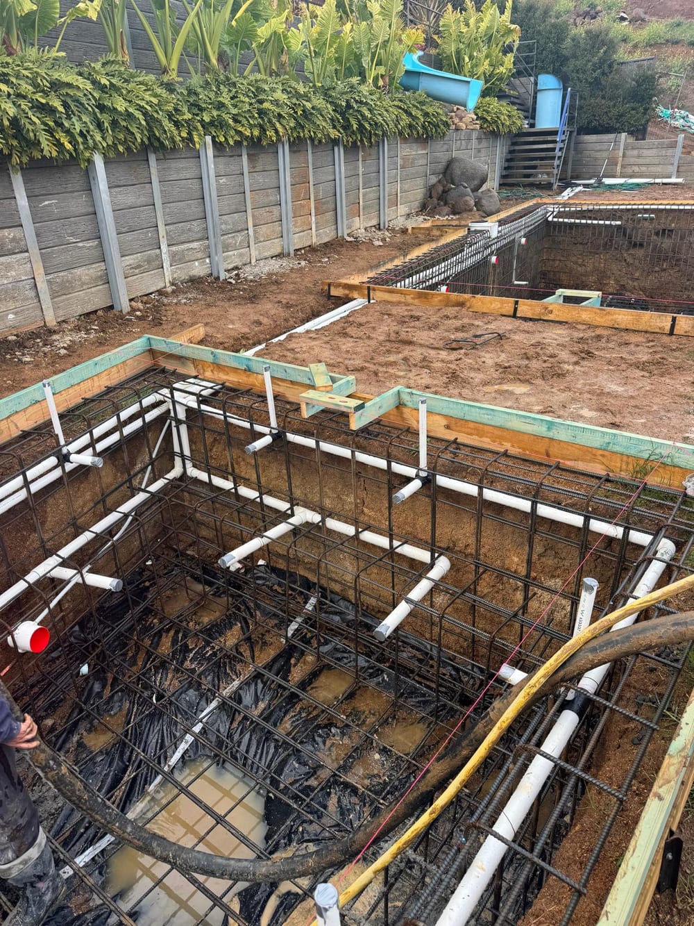 Pool and spa excavations with steel and plumbing below a tropical garden