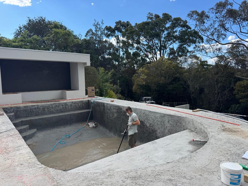 A Nabilton Group crew member hosing out a freshly sprayed concrete pool shell